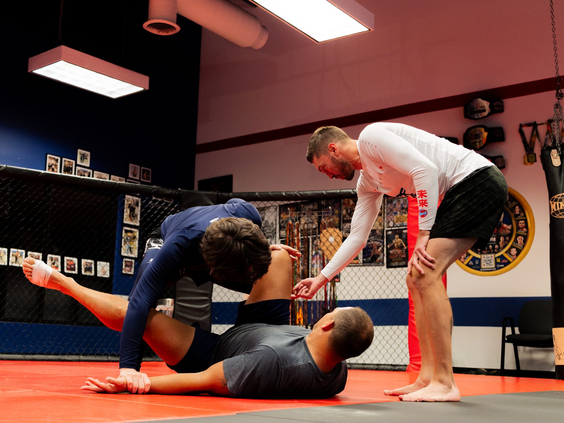 A Loyal Legion coach guiding two students through a no-gi position on the mat.